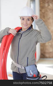 female builder with reel of red pipe on her shoulder