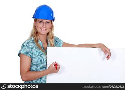 Female builder writing on blank poster