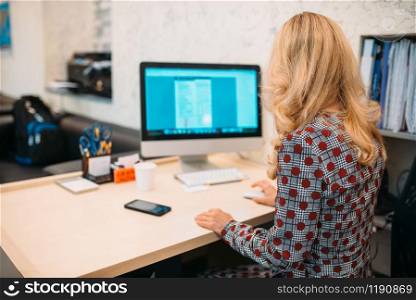 Female business person sitting at the desk and works on computer in office. Secretary or manager workplace