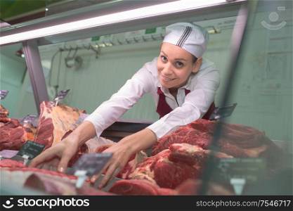female butcher arranging window in store