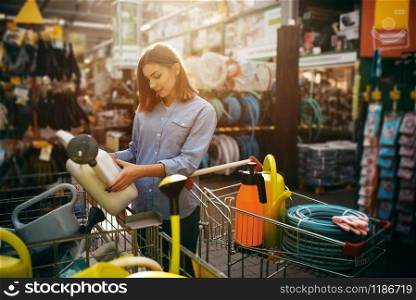 Female buyer choosing gardening tools in shop for gardeners. Woman buying equipment in store for floriculture, florist instrument purchasing. Female buyer choosing tools in shop for gardeners