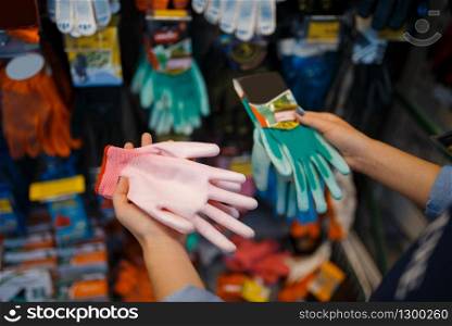 Female buyer choosing gloves, shop for floristry. Woman choosing equipment in store for floriculture, florist instrument purchasing, gardening hobby