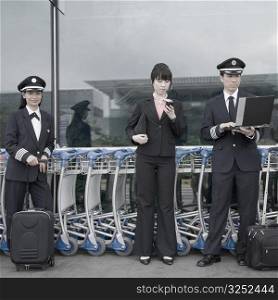 Female cabin crew standing with two pilots at an airport