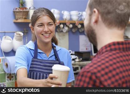 Female Cafe Worker Serving Customer With Takeaway Coffee