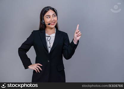 Female call center operator wearing headset and formal suit standing confidently with finger pointing up gesture for product advertisement or HR recruitment on isolated background. Jubilant. Female call center operator wearing headset making finger pointing. Jubilant