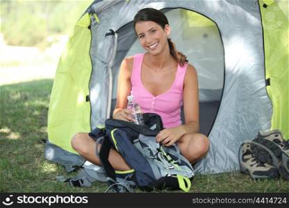 Female camper sat by tent