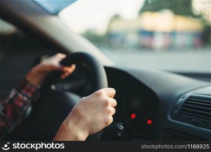 Female car driver beginner clung to the wheel, driving school concept. Automobile exam or test on the street. Female car driver beginner clung to the wheel
