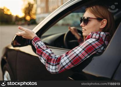 Female car driver in sunglasses, boorish behavior. Woman in vehicle, aggressive automobile driving concept. Female car driver in sunglasses, boorish behavior