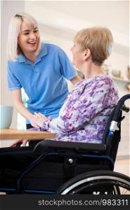 Female Care Assistant Talking To Senior Woman Sitting In Wheelchair At Home