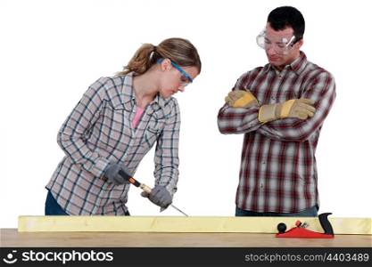 female carpenter at work with male workmate watching her