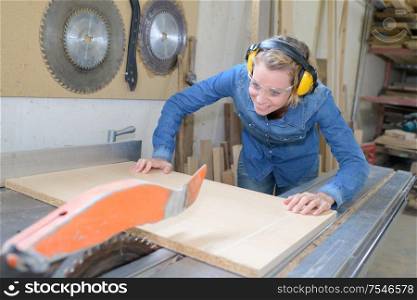 female carpenter cutting plywood using rotating saw