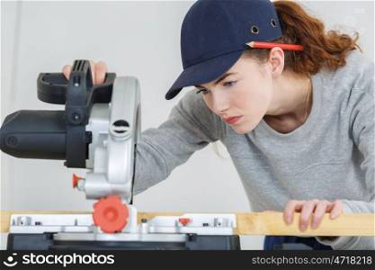 female carpenter cutting wood with a circular power saw