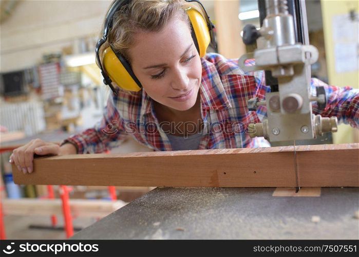 female carpenter cutting wood with an electrical jigsaw