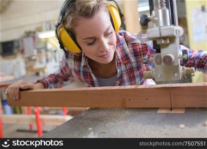 female carpenter cutting wood with an electrical jigsaw