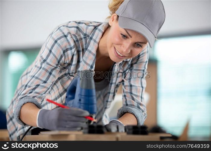 female carpenter marking wood in workshop