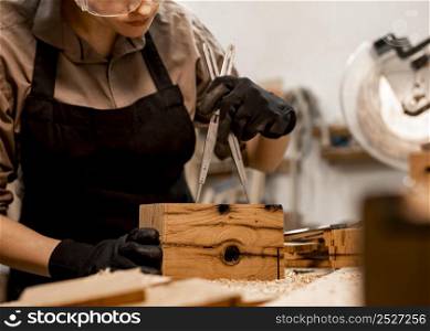 female carpenter office measuring piece wood