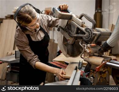female carpenter studio using electric saw