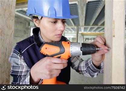 female carpenter using a drill on a wood