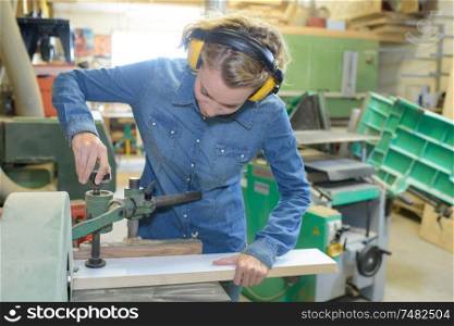 female carpenter using electric sander for wood