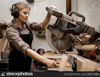 female carpenter using electric saw studio
