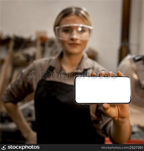 female carpenter with glasses holding smartphone