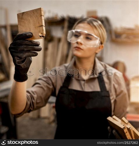 female carpenter with glasses looking piece wood