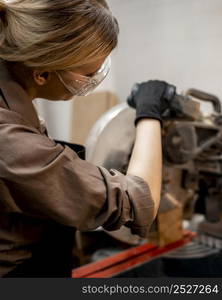 female carpenter with glasses using electric saw