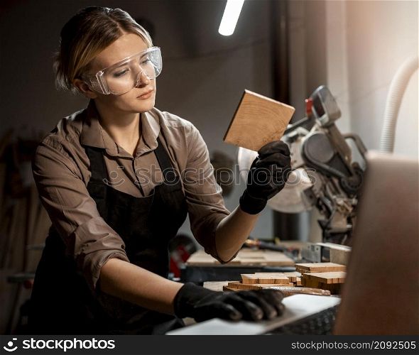 female carpenter with safety glasses looking piece wood studio