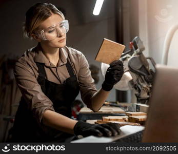 female carpenter with safety glasses looking piece wood studio