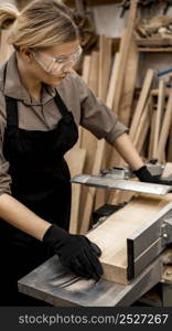 female carpenter with safety glasses sawing wood