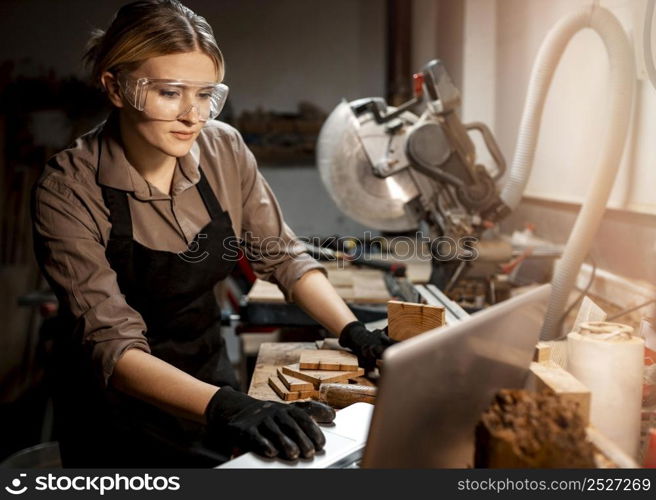female carpenter with safety glasses using laptop