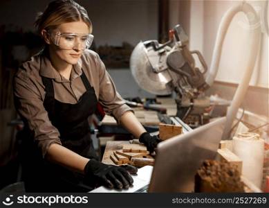 female carpenter with safety glasses using laptop