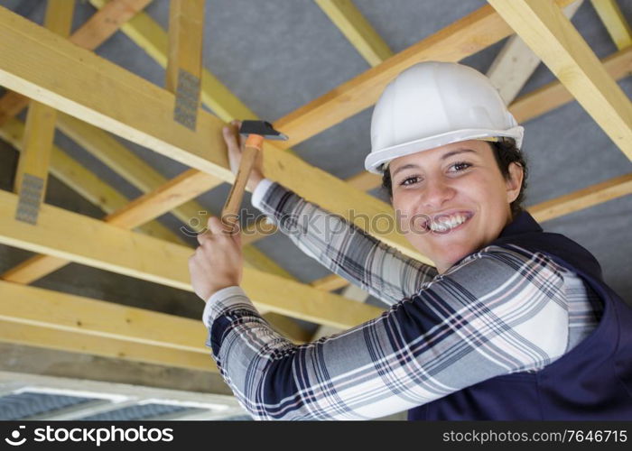 female carpenter working on wooden roof joist