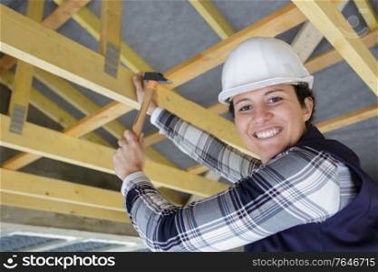 female carpenter working on wooden roof joist
