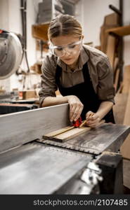 female carpenter working studio with electric saw