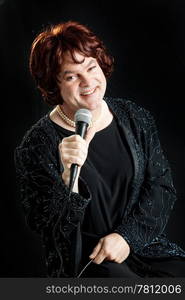 Female celebrity impersonator singing against a black background.