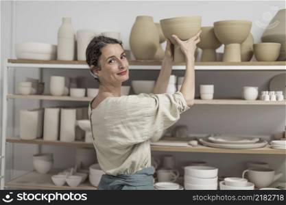 Female ceramist at indoors holding handmade clay product. Conception of pottery