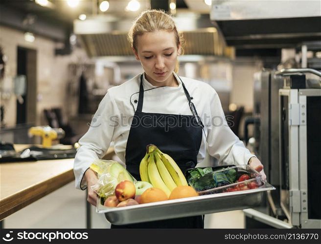 female chef holding tray with fruit