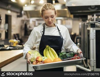 female chef holding tray with fruit
