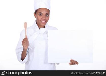 Female chef holding wooden spoon and blank poster