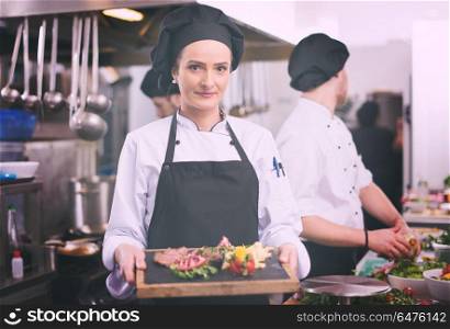 female Chef in hotel or restaurant kitchen holding grilled beef steak plate with vegetable decoration. female Chef holding beef steak plate