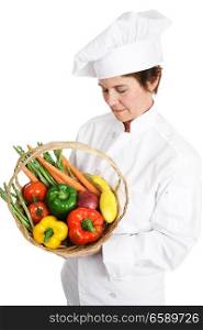 Female chef inspecting a basket of fresh vegetables. Isolated on white.