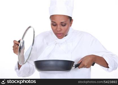 Female chef looking in a pan of food