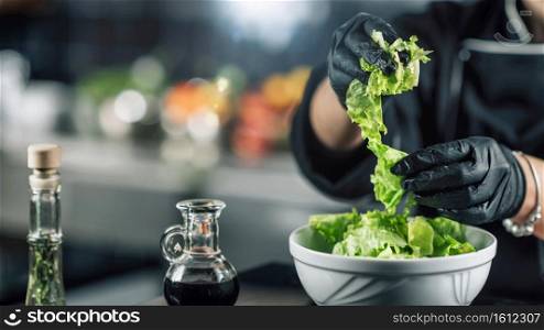 Female chef making healthy vegan salad. Chef’s Hand Preparing a Green Salad 