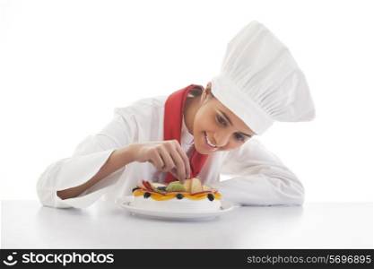 Female chef making mixed fruit cake isolated over white background
