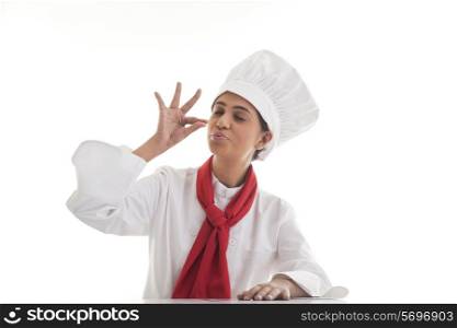 Female chef making tip with her hand in front of mouth to symbolize deliciousness