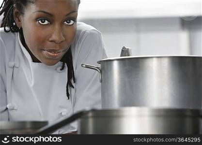 Female chef near saucepan in kitchen, portrait
