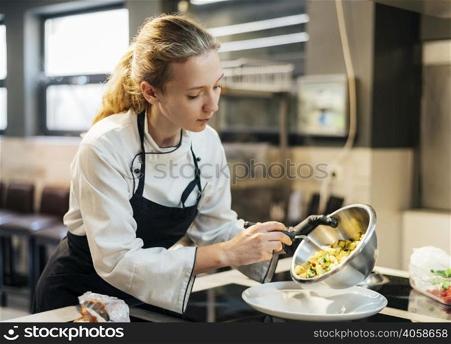 female chef pouring food plate