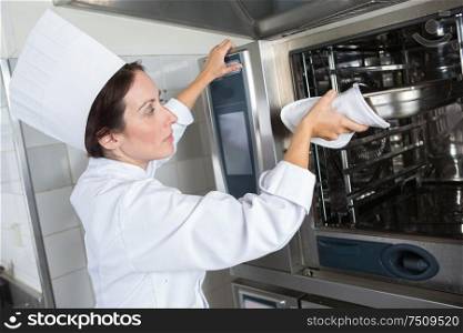 female chef putting something in industrial oven