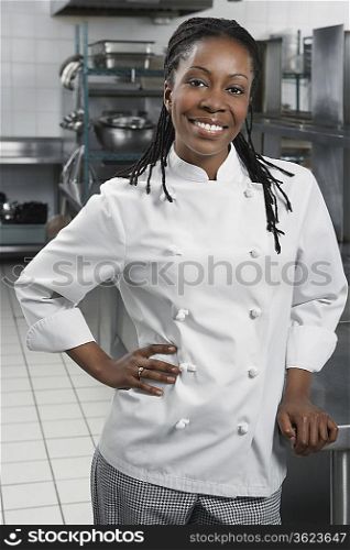 Female chef with hand on hip in kitchen, portrait